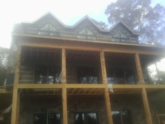 Dormers and porch framing on a large log home under construction — Roof Coating work by our crew in Emmett