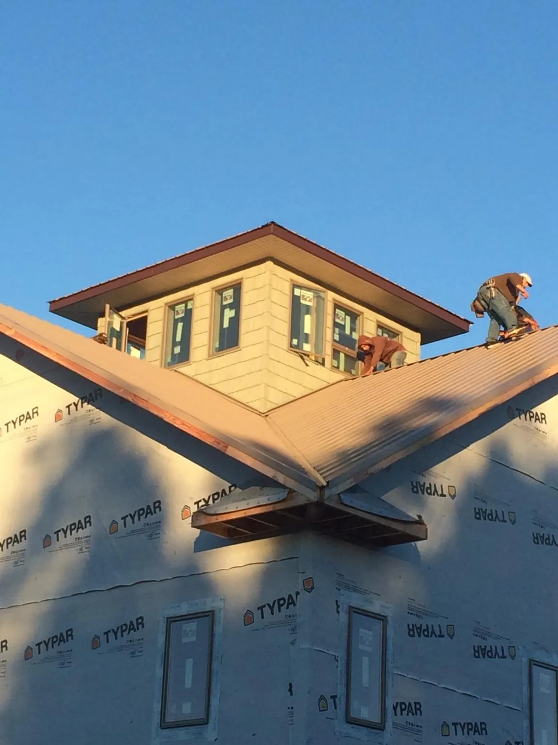 Roofers working around a rooftop cupola on a new metal roof at sunset — Roof Waterproofing in Emmett by Roofing Brothers